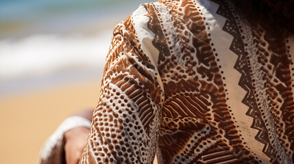 Close-up of the intricate patterns on the woman's clothing, with the spray of the waves in the background
