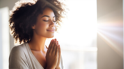 Close-up of a content woman in a sunlit room, hands clasped over heart, a faint smile and closed eyes conveying a moment of gratitude
