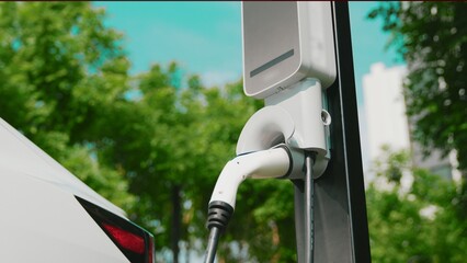 EV electric car charging in green sustainable city outdoor garden in summer. Urban sustainability...