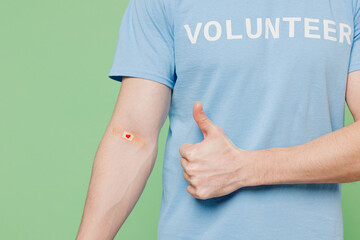 Close up cropped young donor man wear blue t-shirt title volunteer adhesive plaster on hand show...