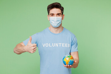Young man wear protective mask blue t-shirt white title volunteer hold in palms earth globe show...