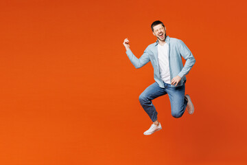 Fototapeta na wymiar Full body young happy excited fun man he wears blue shirt white t-shirt casual clothes jump high play air guitar look camera isolated on plain red orange background studio portrait. Lifestyle concept.