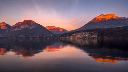 Fototapeta na wymiar Paysage du lac d'Annecy en Haute-Savoie au coucher du soleil en hiver entouré de montagne dans les Alpes françaises