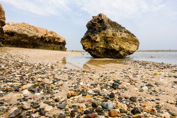 huge coral rock lying at the beach with lot of colorful stones and corals during ebb