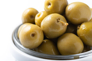 Green olives in white bowl isolated on white background. Close up