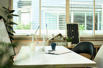 Windmill models and business documents on white table in office. Alternative green energy concept