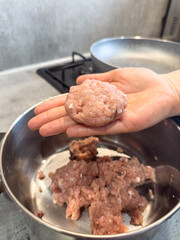 Female hands make meatballs with red fat mince, close up