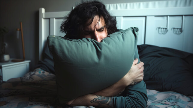A missleeped man laying in bed holds a pillow, providing comfort and support while resting.