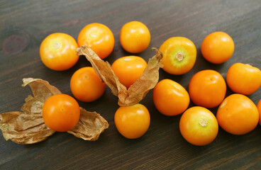 Heap of vivid yellow orange ripe Cape Gooseberries scattered on wooden background