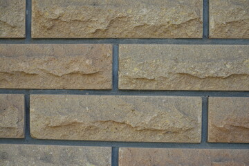 Macro of beige brick veneer wall with grey mortar joints