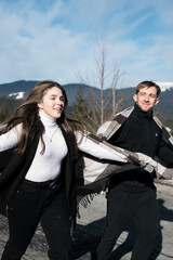 A couple in love is having a romantic date while traveling. A man and a woman are posing against the backdrop of snowy mountains, drinking tea. Travel concept