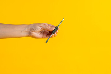 A screwdriver tools in hand on yellow background
