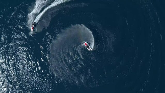 Three Young Man Drawing Circles with Jet-Skis. Birds Eye Drone View