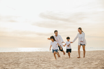 Cheerful family with happy parents and children running on the beach. Laughter fun and joy during summer holiday. Carefree moments of family bonding captured in a snapshot. Family on beach vacation