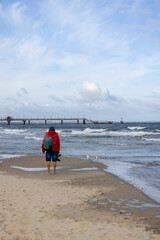 Man walking bare feet on the sand by the water of the Baltic Sea near the pier, Island Wolin, Miedzyzdroje, Poland