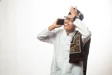 Brown skinned Asian Muslim man is calling happily in studio on white background, religious Islamic lifestyle concept