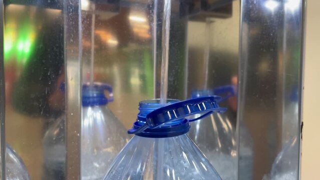 Drinking water bottling process. A five-liter plastic bottle in a drinking water vending machine. Close-up. The bottle is filled with drinking water. Water for drinking and cooking is healthy.