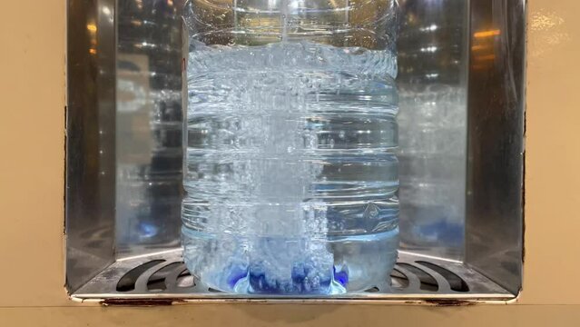 Drinking water bottling process. A five-liter plastic bottle in a drinking water vending machine. Close-up. The bottle is filled with drinking water. Water for drinking and cooking is healthy.