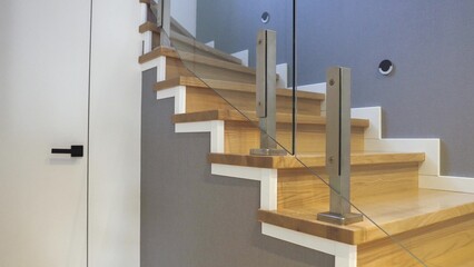 Interior design stylish wooden stairs inside the house with modern glass railings and walls...