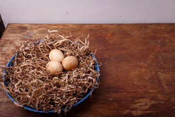 Plate decorated as bird nest with brown colored eggs on rustic background. Happy Easter. Place for text