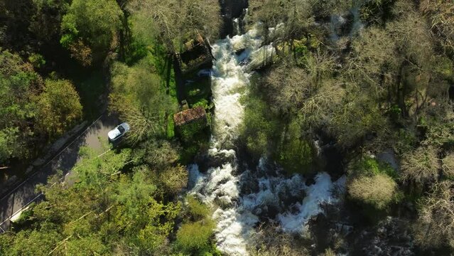 Aerial footage of Zas River flowing amid dense woods near Castriz village, A Coruna, Galicia, Spain