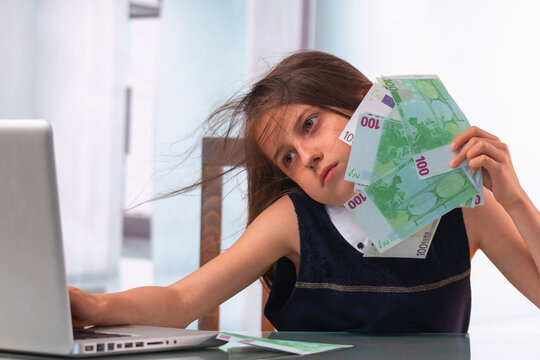 Conceptual image: Teaching kids about money. Portrait of young beautiful girl working online and counting US Dollar money.