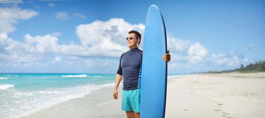 Man with a surfing board standing on a beach