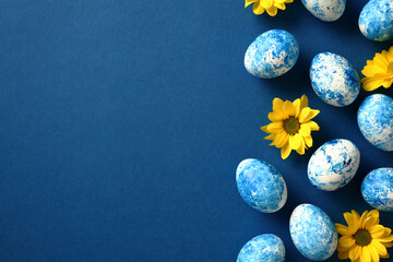 Dark blue background with Easter eggs and yellow flowers, copy space for text and greetings