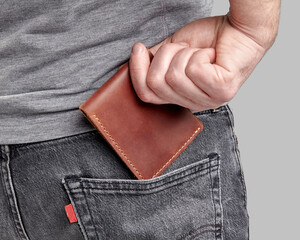 Man inserting personalized leather wallet with embossed initials into pocket