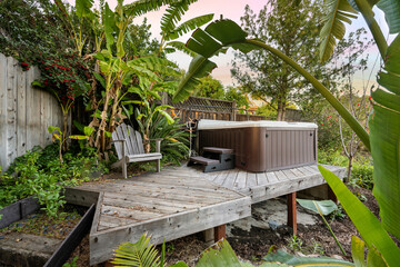 Wooden deck featuring an outdoor hot tub surrounded by lush greenery