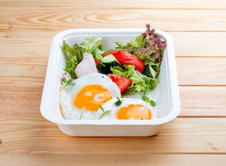 Fried eggs and turkey. Healthy diet. Takeaway food.  On a wooden background.