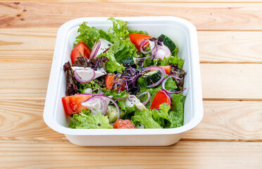 Greek salad with feta cheese. Healthy diet.Takeaway food. On a wooden background.