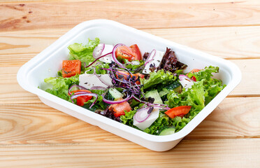 Greek salad with feta cheese. Healthy diet.Takeaway food. On a wooden background.