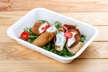 Caneloni with ricotta cheese and spinach. Takeaway food. On a wooden background.