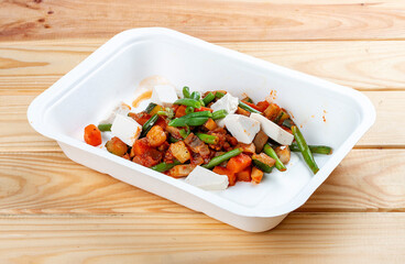 Sautéed vegetables. Healthy diet. Takeaway food. Ecological packaging. On a wooden background.