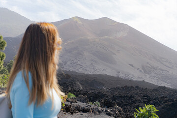 woman with sunglasses looks at the tajogaite volcano from a viewpoint