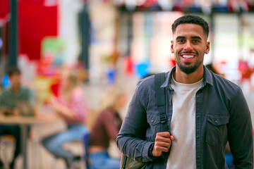 Portrait Of Smiling Male University Student With Backpack Standing Inside College Building