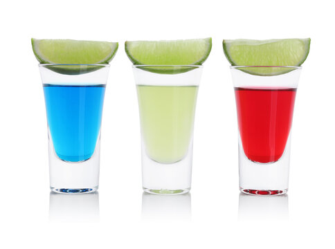Different shooters in shot glasses and lime wedges isolated on white. Alcohol drink