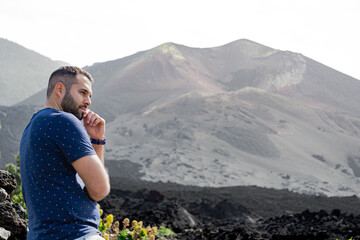 man standing thoughtfully looks at the lava flow from a volcano