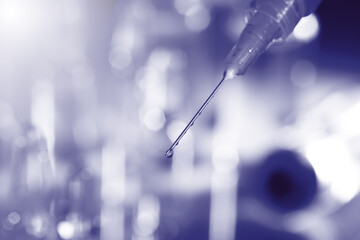 Syringe with medicine against blurred background, toned in purple