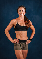 Smiling muscular female fitness model posing