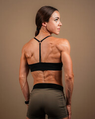 Attractive muscular female fitness model posing showing back