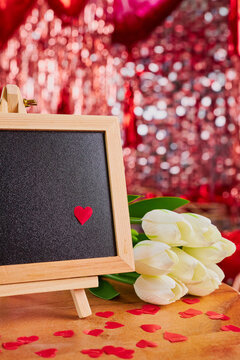 Valentine's day greeting card with chalkboard, white tulips flowers bouquet and glasses on wooden background. Copy space