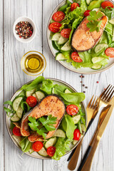 Fresh vegetable salad and baked salmon in a plate on the table. Mediterranean diet concept. Top view