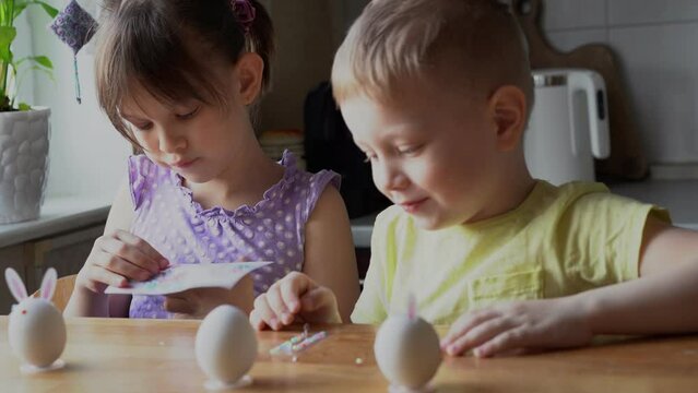 Little girl and boy decorate easter eggs at home. Preparing for Easter concept. Selective Focus