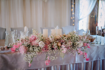Valmiera, Latvia - July 7, 2023 - Elegant wedding table with a pink and white floral arrangement and candles.
