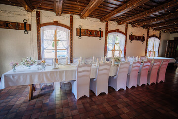 Valmiera, Latvia - July 7, 2023 - Rustic wedding reception interior with decorated tables, chairs, and hanging lights.