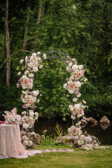 Valmiera, Latvia - July 7, 2023 - A floral arch and table by a river, set up for a wedding or event.