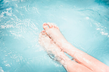 Fototapeta premium Child bare feet under blue water in a swimming pool.
