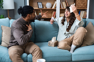 Unhappy young woman sitting on sofa with pregnancy test, African American husband screaming at her, indoors. Millennial family having conflict over unexpected childbearing, argue over results - obrazy, fototapety, plakaty